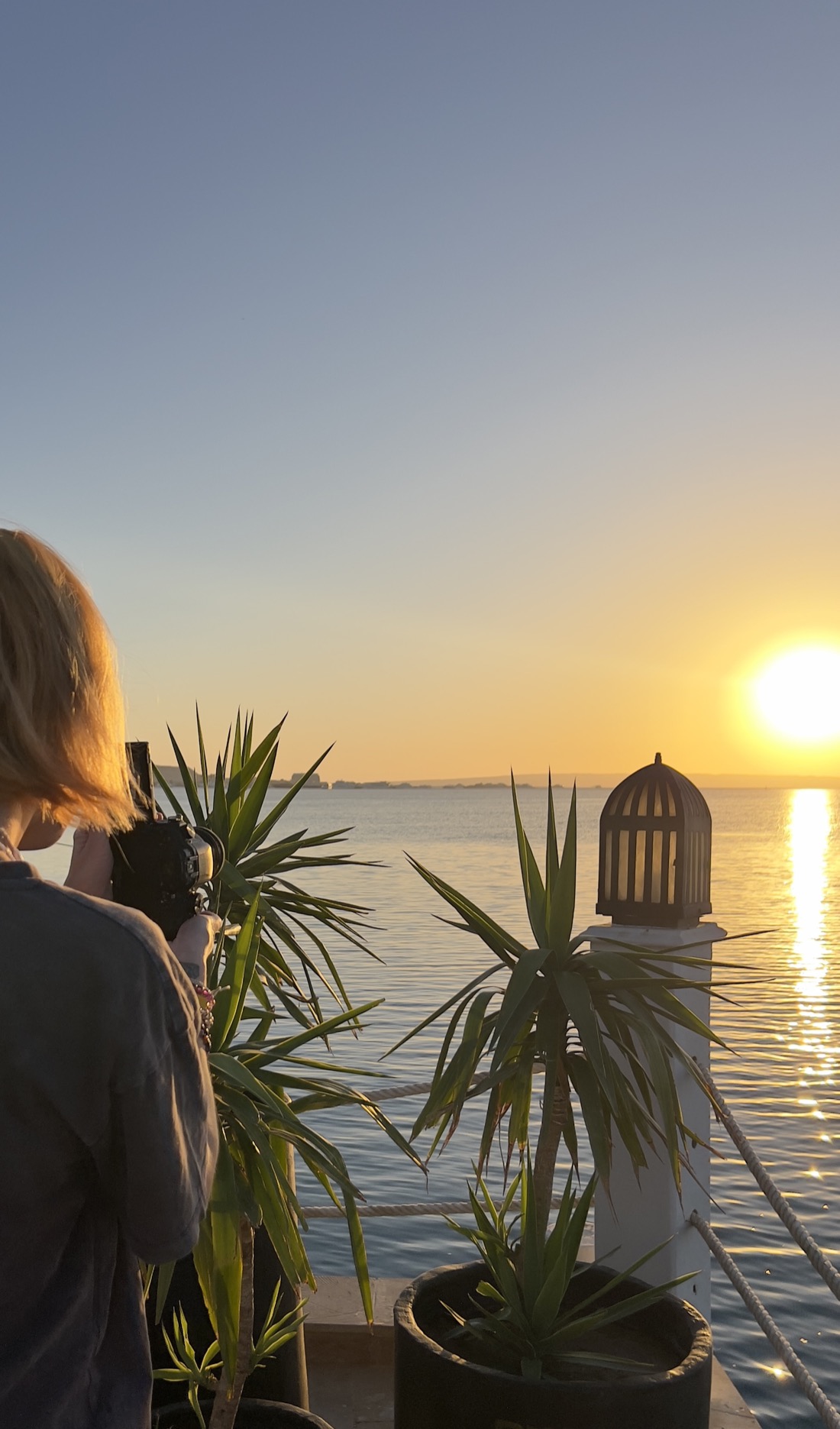 A PRES. creator shooting content at golden hour by the sea.